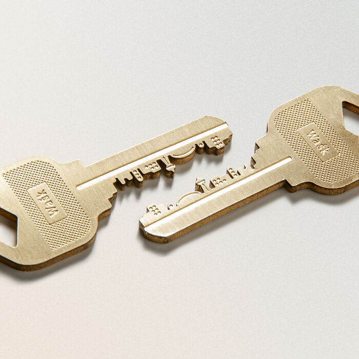 Unusual and conceptual product design of a wooden key split into two separate pieces on a plain background.