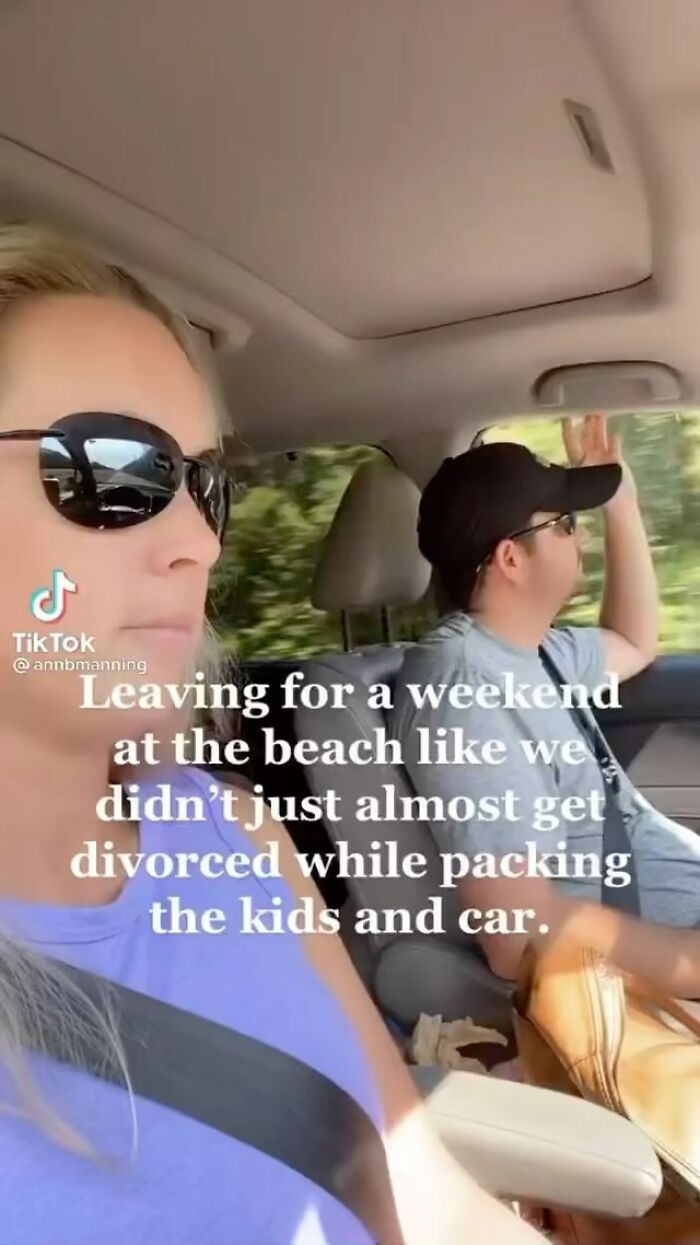 Man driving with hand raised, woman beside him in sunglasses, text overlay on fatherhood humor.