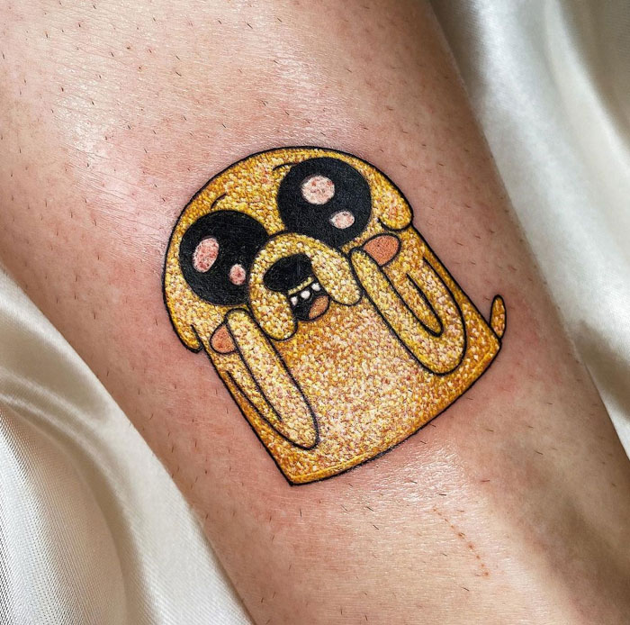 Glitter tattoo of a golden cartoon dog on skin, sparkling and vibrant.