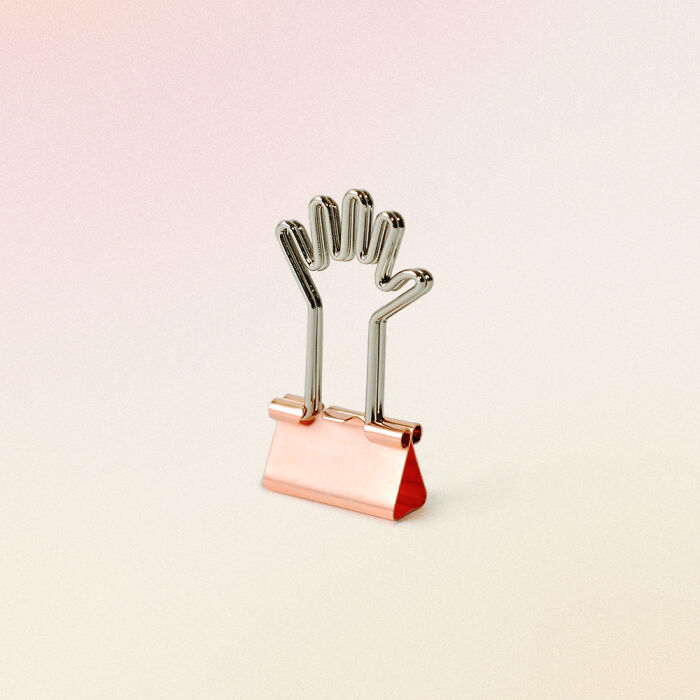 Unusual and conceptual product design of a paper clip shaped like a hand on a soft gradient background.