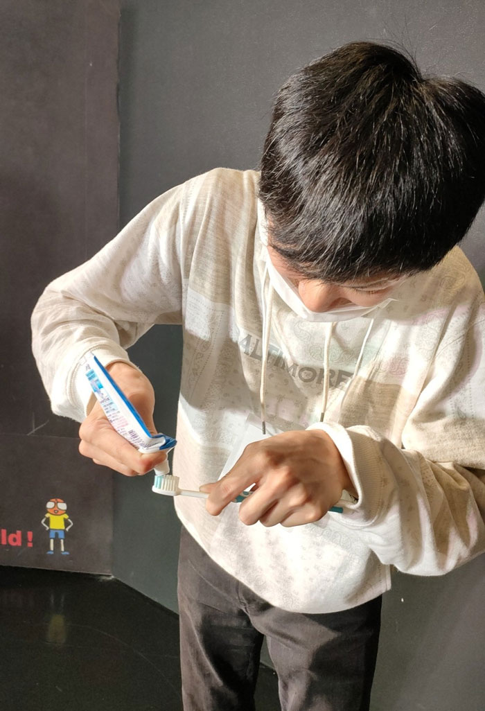 Person in mundane Halloween costume, applying toothpaste to a toothbrush, capturing a hilariously boring theme.