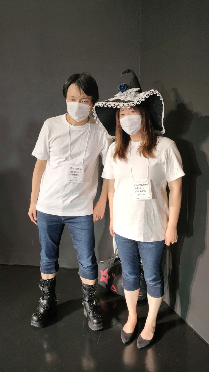 Two people in mundane Halloween costumes, wearing masks and plain white shirts, one with a witch hat.