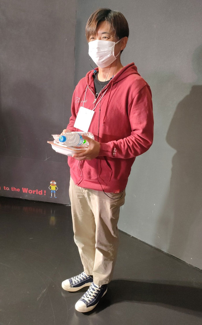 Person in a red hoodie and mask, holding a clipboard and water bottle, embodies a mundane Halloween costume.