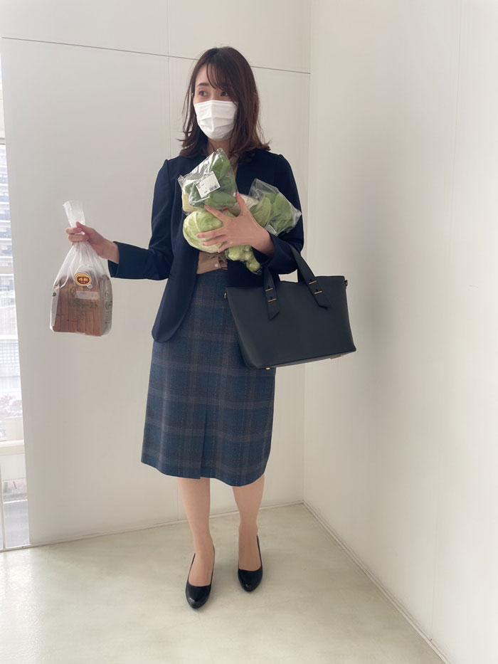 Person in a mundane Halloween costume holding groceries, wearing a mask and business attire.