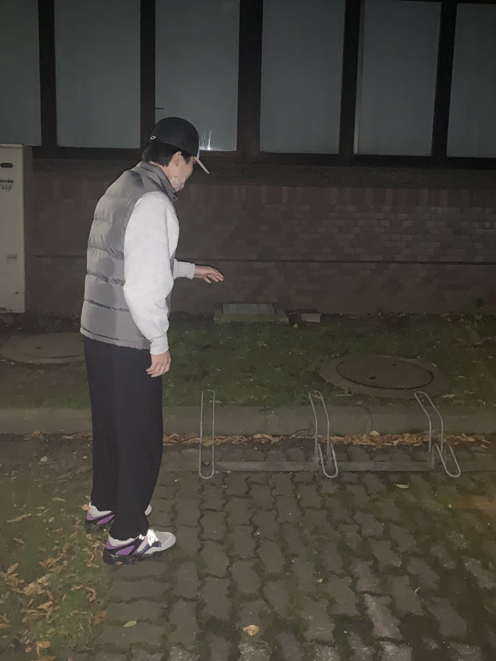 Person in casual clothing mimicking a mundane Halloween costume, pretending to avoid an invisible obstacle at night.