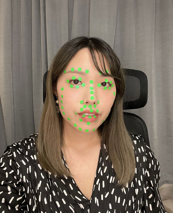 Woman in patterned shirt with green dots on face for Mundane Halloween costume.