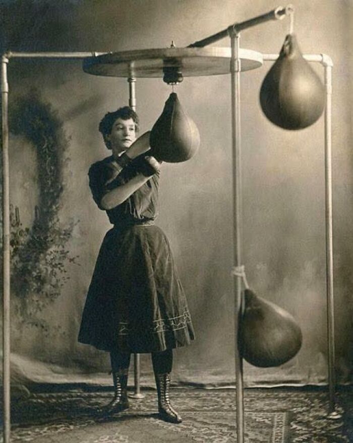 A Young Woman In A Skirt Working Out With Boxing Gloves And A Punching Bag, 1890