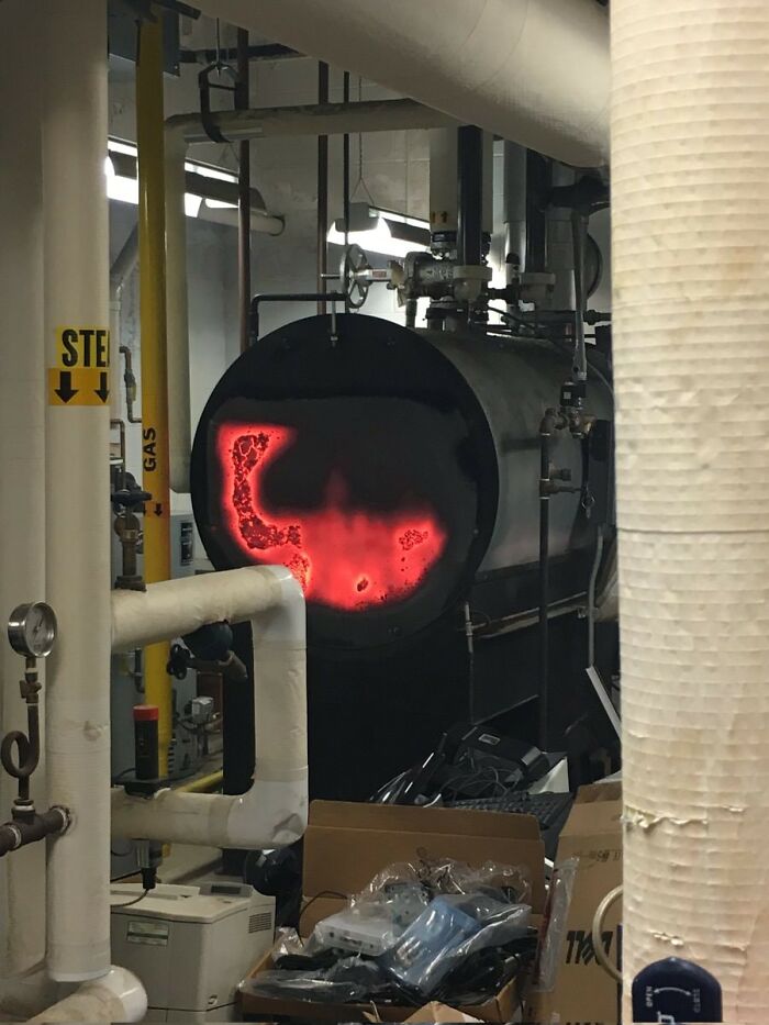 A lit furnace in an industrial setting surrounded by pipes and various equipment, highlighting disregard for safety regulations.