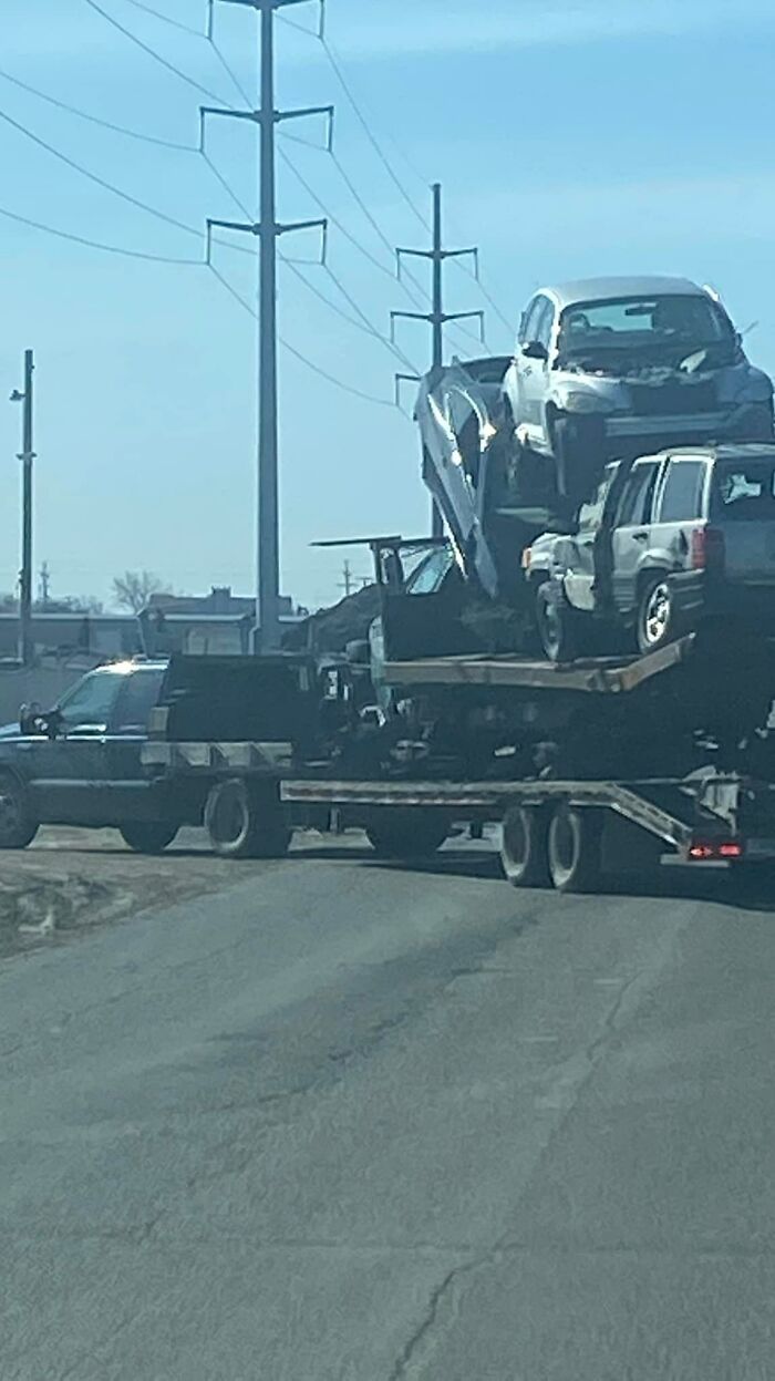 Cars stacked unsafely on a trailer defying OSHA safety norms on a highway.