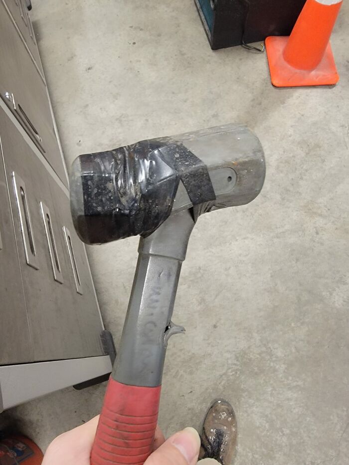 A hammer with a broken handle is held together with tape, highlighting disregard for OSHA safety regulations.