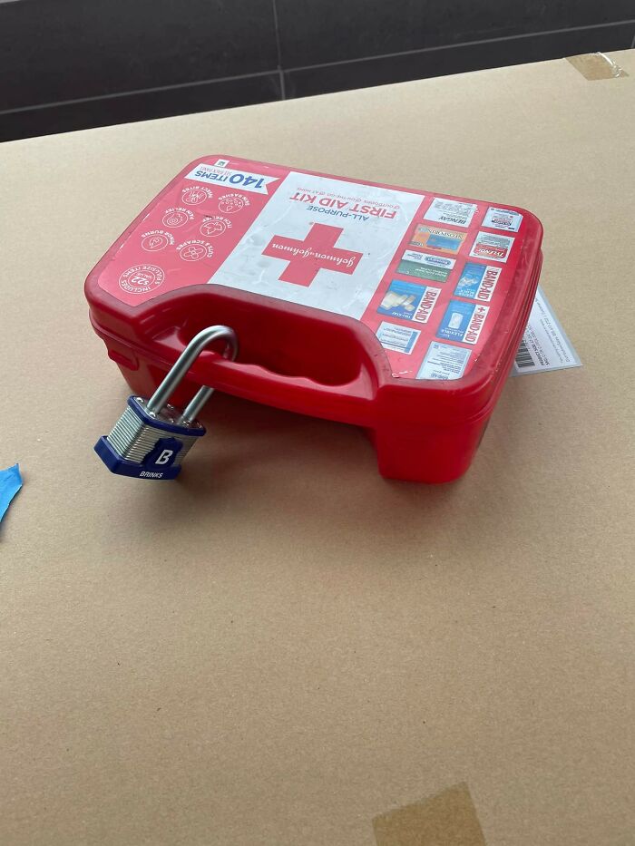 Red first aid kit secured with a padlock, highlighting disregard for OSHA safety regulations.
