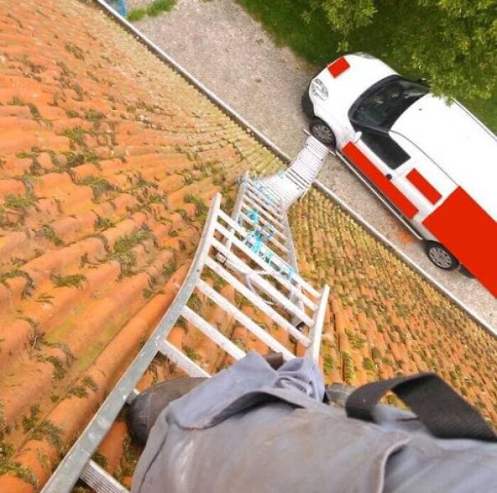 Unsafe ladder use on a roof with a van below, ignoring OSHA safety regulations.