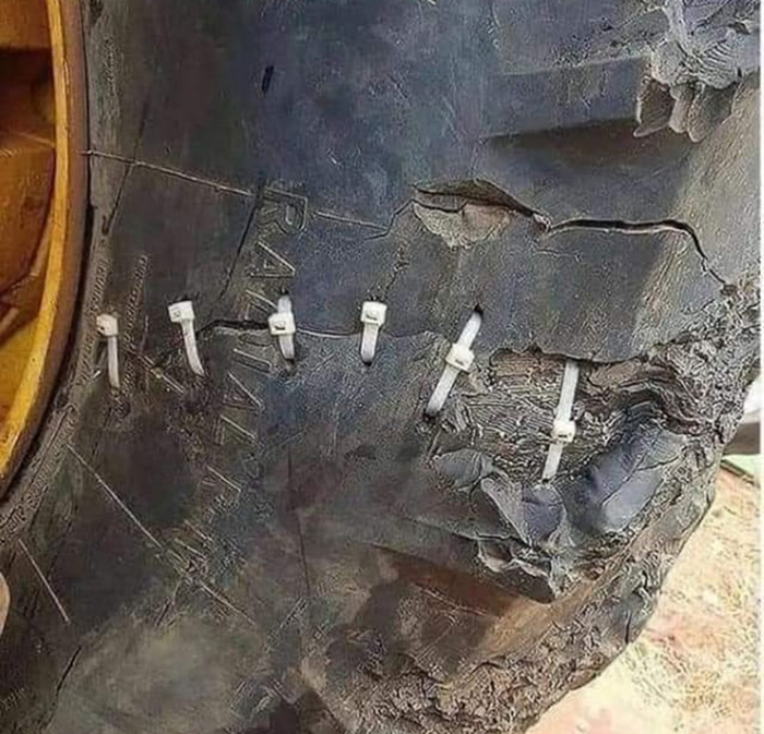 Damaged tire fixed with zip ties, disregarding OSHA safety regulations for a practical solution.