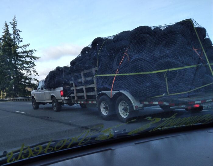 Truck hauling a large load of tires on a highway, not adhering to OSHA safety regulations.