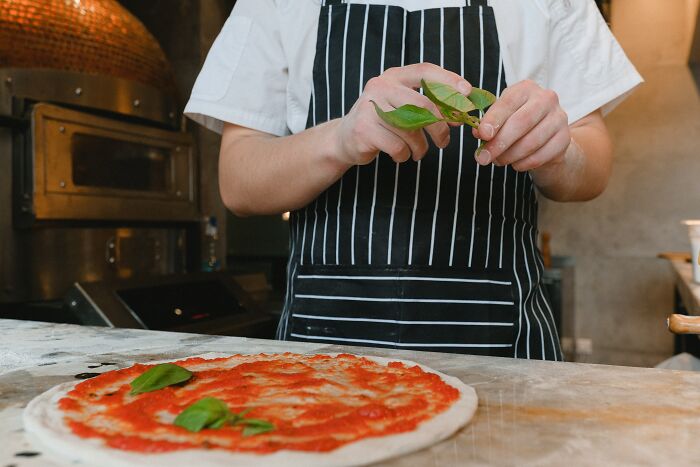 Pizza Chef Putting Basil Leaves On Fresh Pizza 