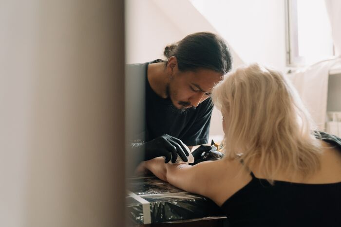 Tattoo Artist Tattooing A Woman's Arm 