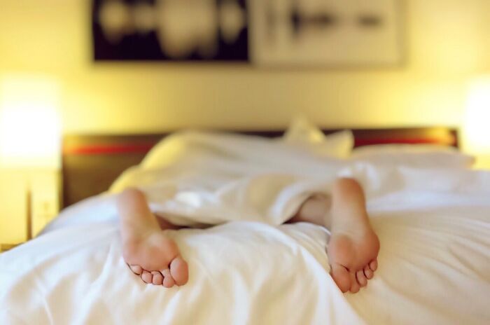 Person Lying In Bed With Feet Out OF Blanket 