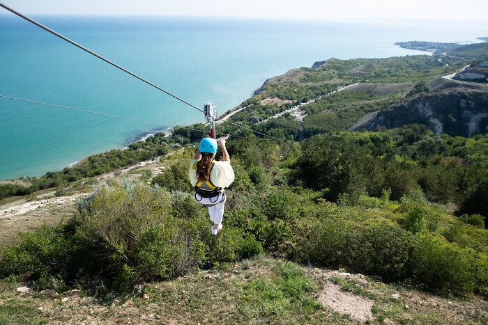 Woman Zip Lining From The Mountain Top 