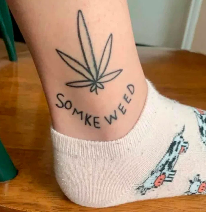 Tattoo of a cannabis leaf above misspelled text "SOMKE WEED" on someone's ankle.