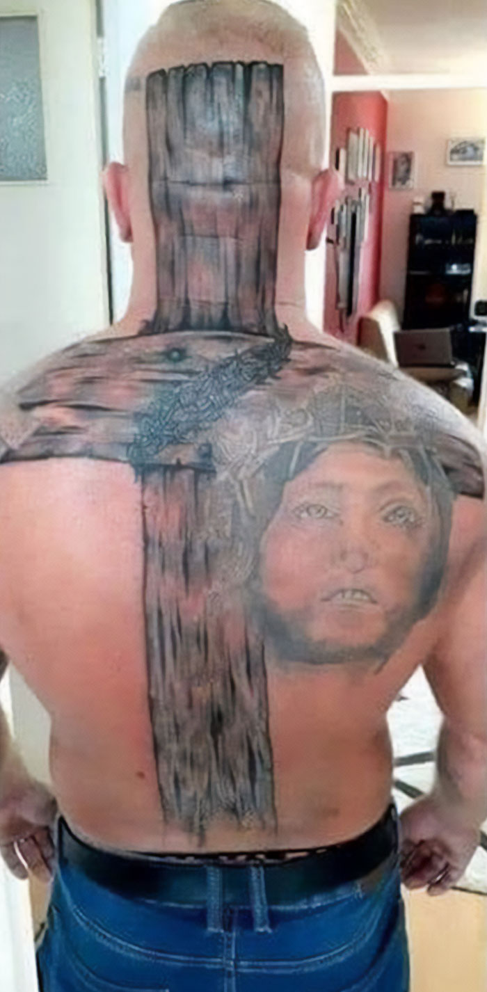 Man with a large back tattoo depicting a wooden cross and a face, highlighting bad tattoo choices.