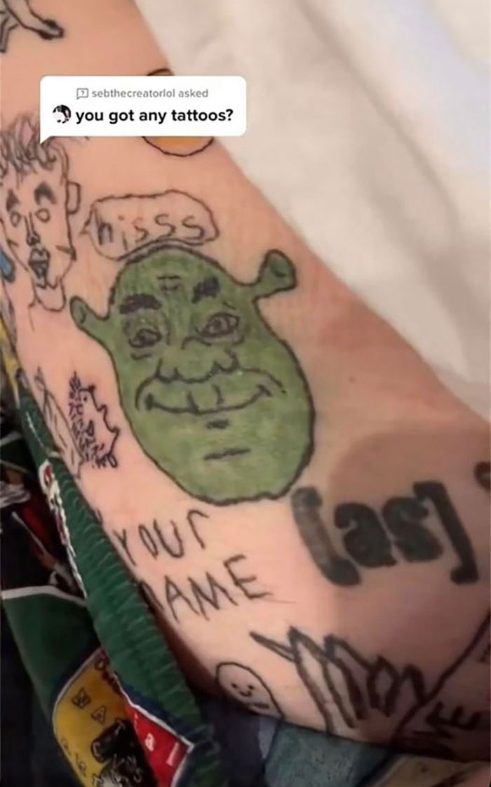Poor-quality tattoos on a person's arm, including a green face of Shrek and various doodles.
