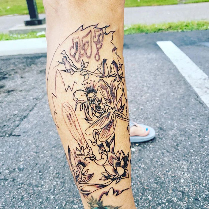 Abstract leg tattoo with flowers and music notes on pavement background, showcased in tattoo group.
