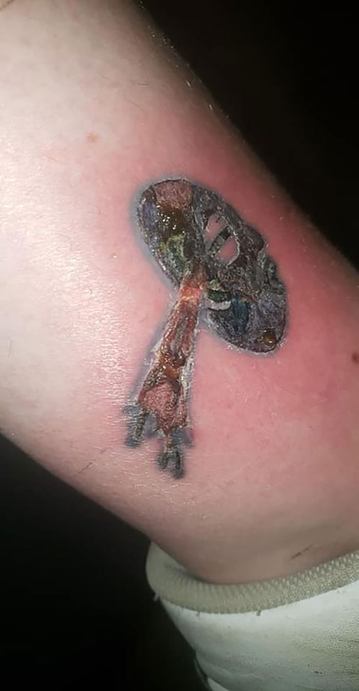 Close-up of a poorly designed tattoo on the arm, featuring blurred and faded colors.