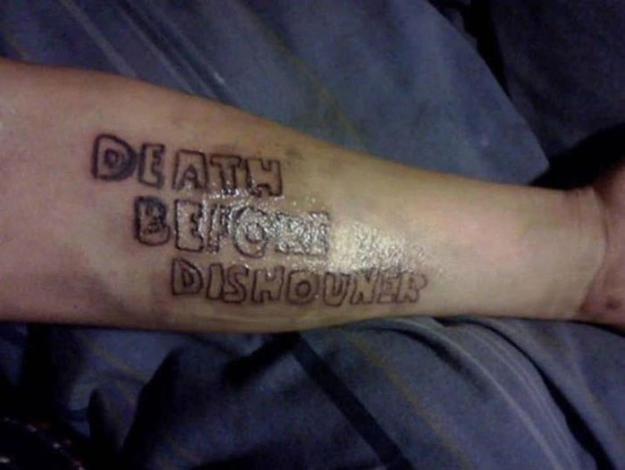 Misspelled tattoo reading "Death Before Dishouner" on forearm. Bad tattoo shared on Facebook group.