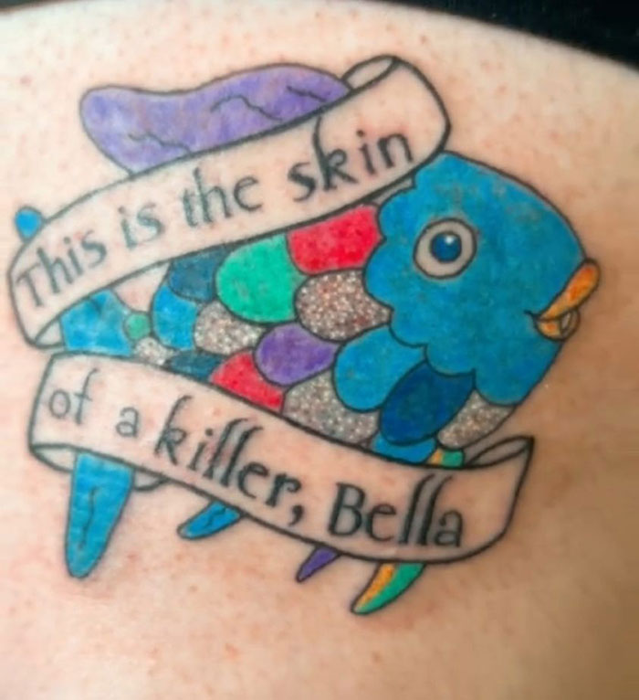 A colorful fish tattoo with text ribbon, showcasing a questionable tattoo choice.