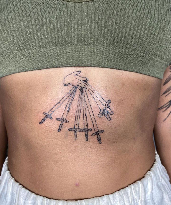 A tattoo of a hand holding puppet strings on a person's abdomen, symbolizing bad tattoos.