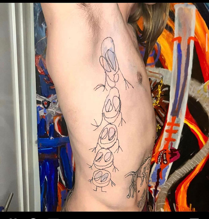 Bad tattoos example of shaky cartoonish figures inked on a person's side with colorful artwork in the background.