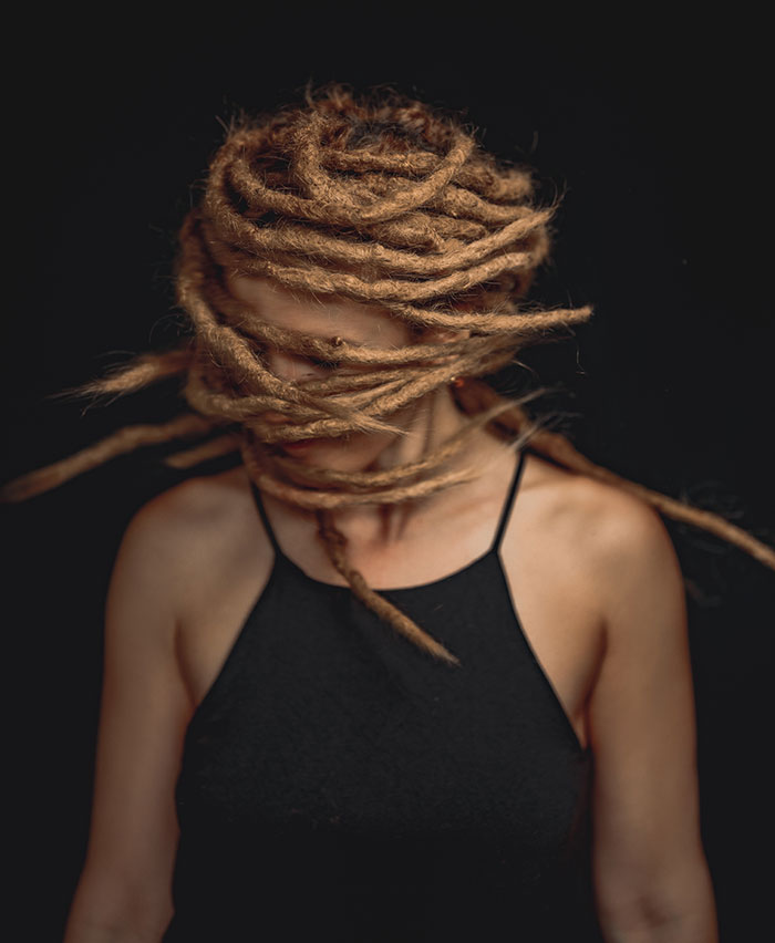 Woman enjoying "me time" with unique hairstyle, wearing a black top, in a contemplative pose.