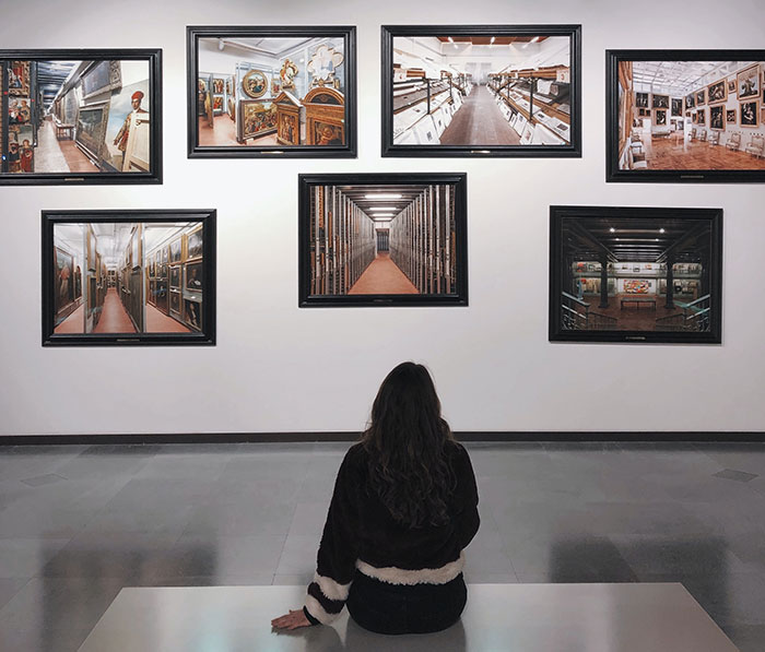 Person enjoying "me time" at an art gallery, observing a collection of paintings.