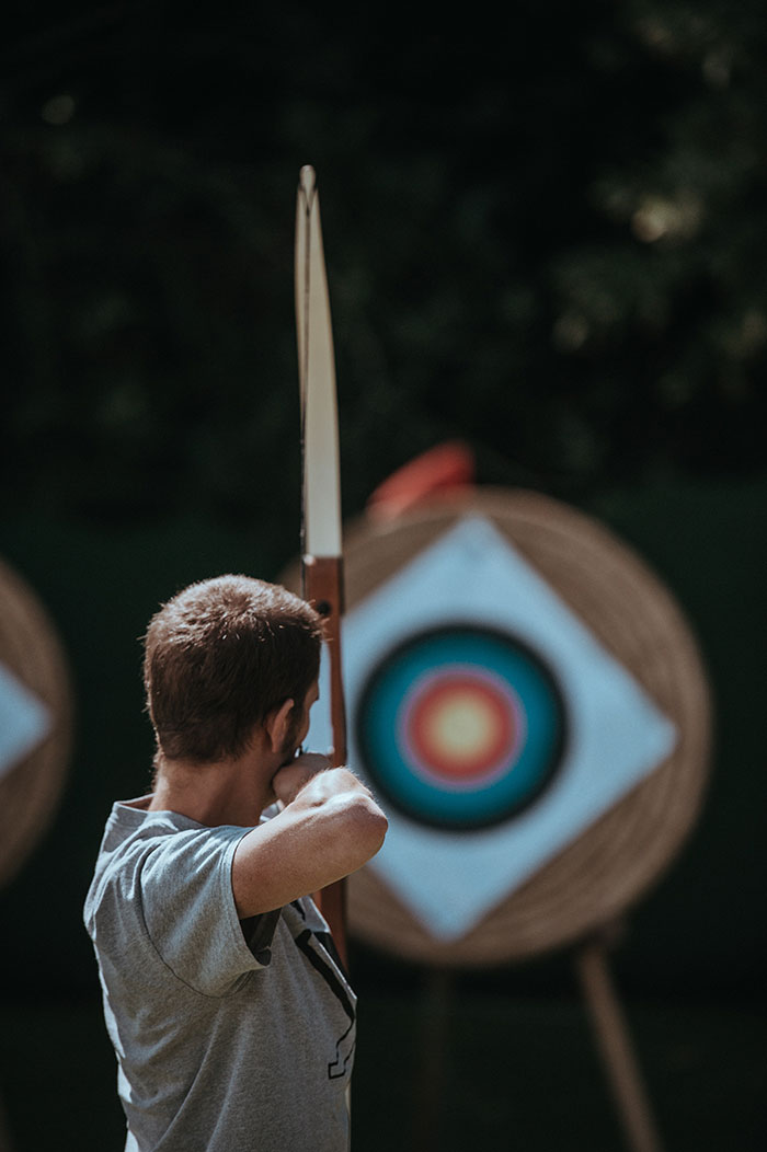 Person practicing archery alone at a target range, enjoying some "me time" with a bow and arrow.