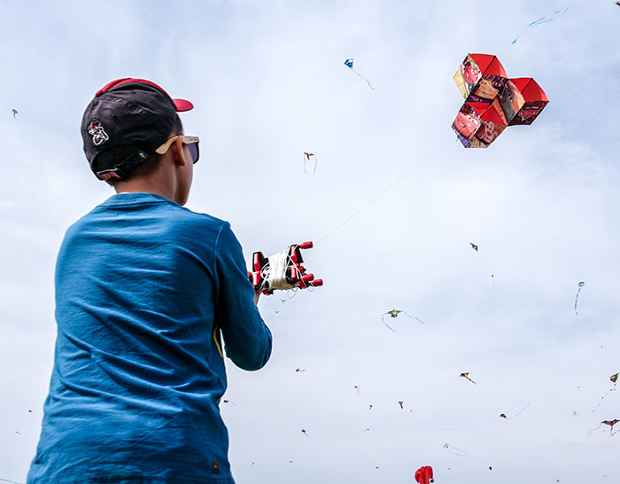 Child enjoying "me time" while flying a colorful kite in a clear blue sky.