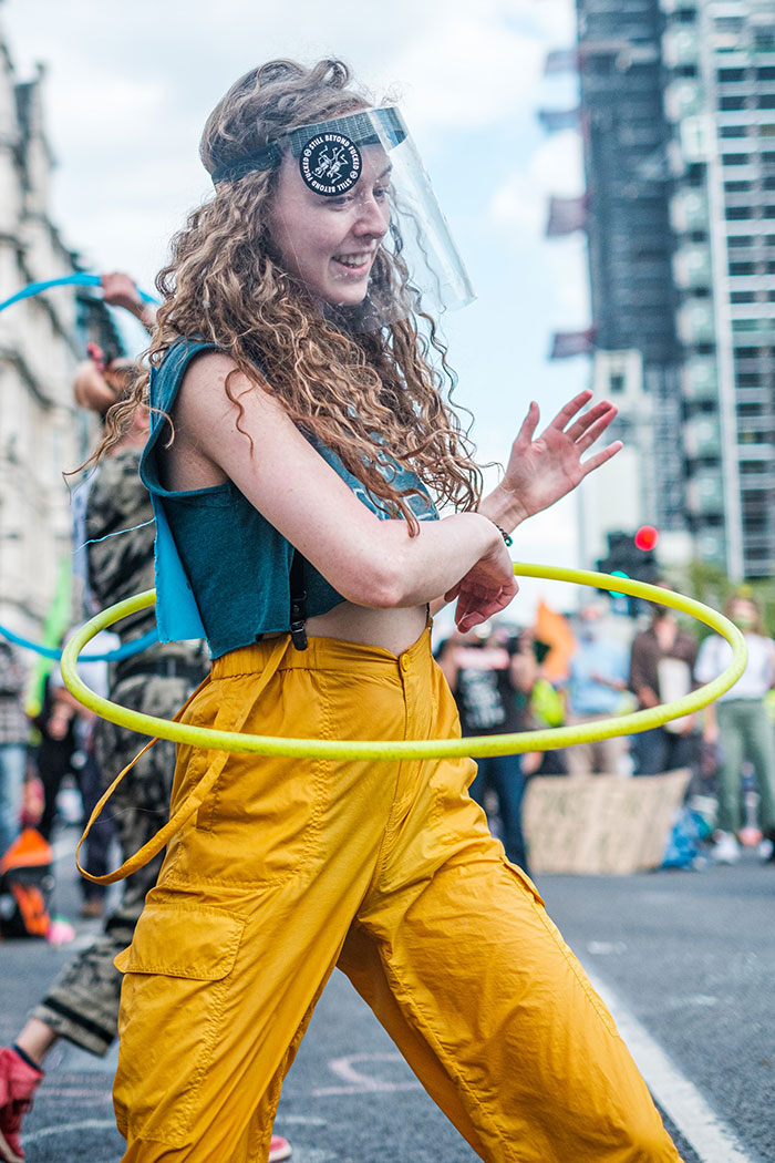 Person enjoys some me time by hula hooping outdoors, wearing a visor and casual clothes.