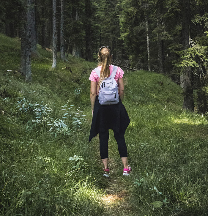 Person enjoying a nature walk with a backpack, embodying me time amidst lush greenery.