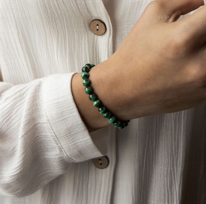 Woman enjoying me time, wearing a green bracelet and a white blouse, focusing on self-care.