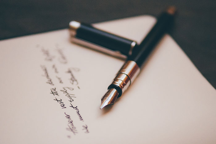A fountain pen rests on handwritten letter, ideal for reflecting during "me time."