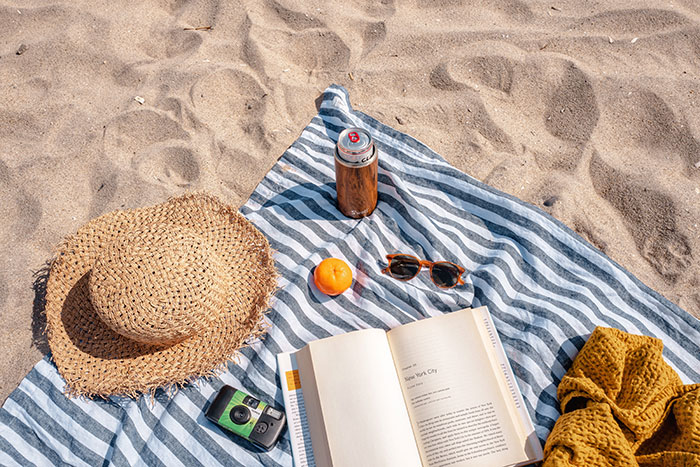Books, sheet, phone, and glasses on a beach for relaxing "me time."