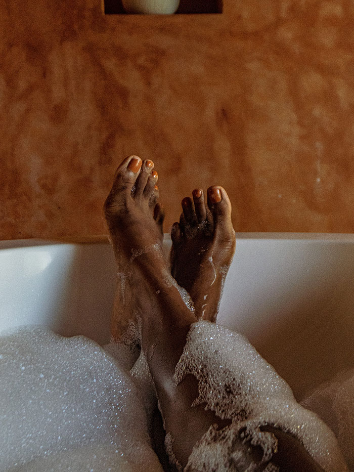 Woman enjoying a relaxing bath for "me time" with bubbles covering her legs.