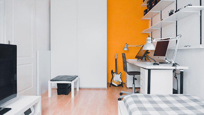 Minimalist white room decor with desk, shelves, and guitar, ideal for enjoying "me time" by yourself.