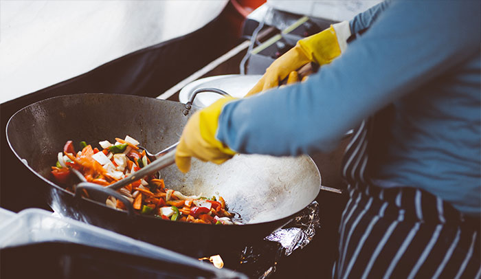 Person making food in a wok pan 
