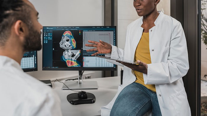 Two medical professionals discussing MRI scans on a computer screen, illustrating examples of people having the worst birthdays.