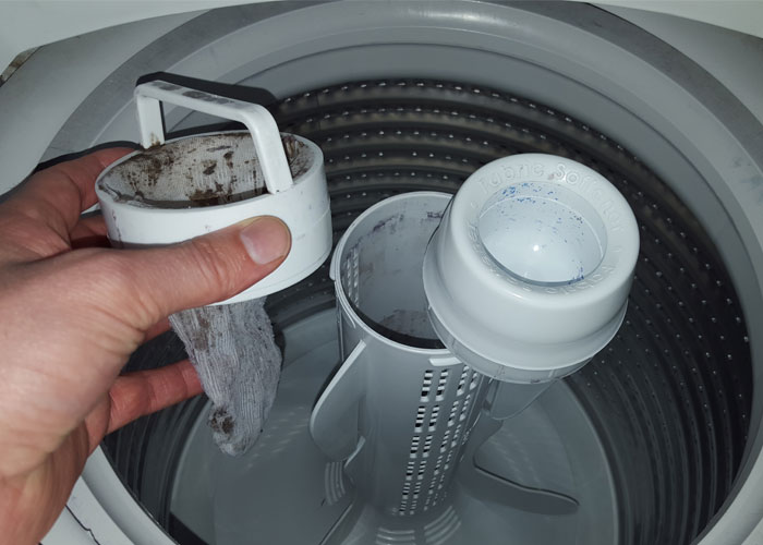 Hand cleaning a washing machine lint filter with homeowning maintenance tips in mind.