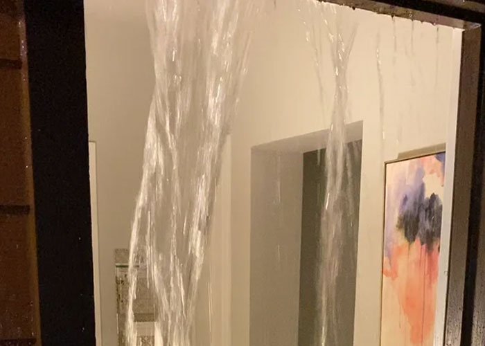 Water pouring through a window crack inside a home, illustrating critical homeowning issues shared by dads in a thread.