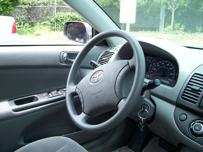 Interior view of a Toyota car showing the steering wheel, dashboard, and ignition with keys, illustrating basic facts knowledge.
