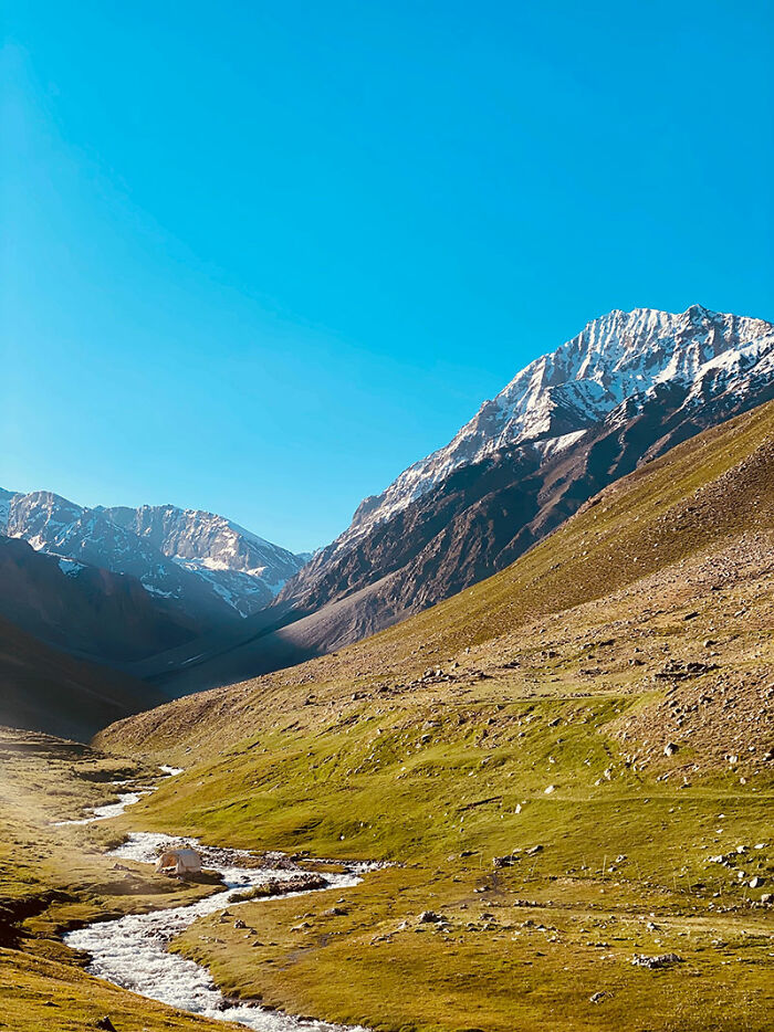 Snow-capped mountains and green valley in Afghanistan, showcasing the country's natural beauty and landscape while traveling.