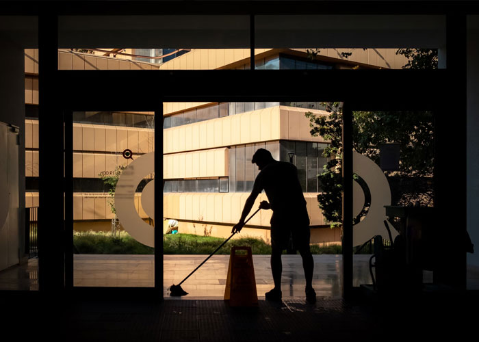 Silhouette of a worker mopping the floor near a wet floor sign, highlighting disturbing things people experienced while at work.