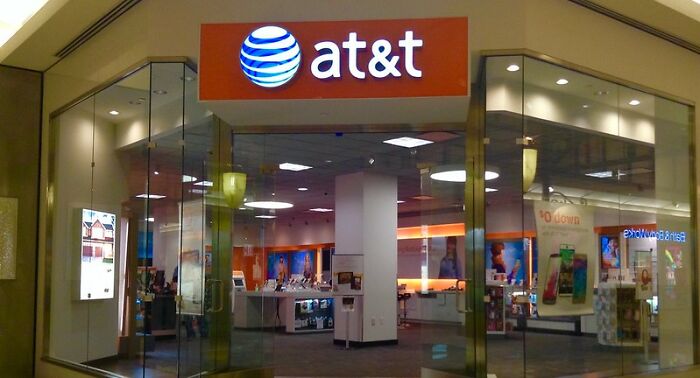 AT&T store front inside a shopping mall with glass walls and illuminated brand signage visible.